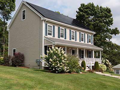 Two-story hillside home with beige siding. Lots of floral landscaping and a
              freshly mowed lawn.